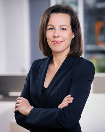 Foto: Dr. Stefanie Höger steht mit verschränkten Armen in einem modernen Büro.