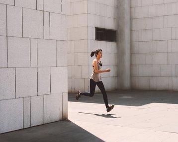 Eine Person läuft in sportlicher Kleidung in einem modernen, minimalistischen Umfeld mit hellen Wänden.
